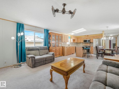 Open-concept living space featuring a kitchen with light wood cabinetry, a central island, and stainless steel appliances - 151 3400 48 Street, Stony Plain, AB - Indoor Photo Showing Living Room