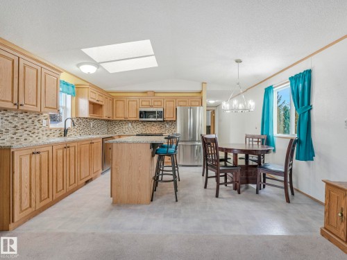 Kitchen featuring wood-finish cabinetry, stainless steel appliances, a mosaic tile backsplash, and a skylight - 151 3400 48 Street, Stony Plain, AB - Indoor