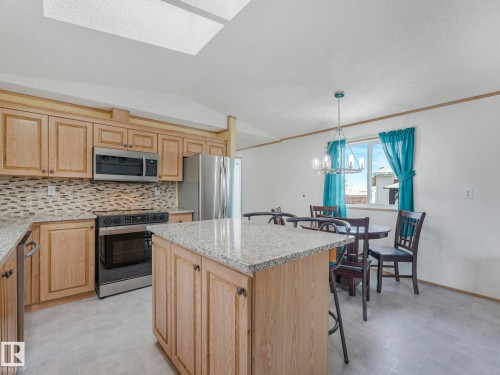 Kitchen featuring light wood cabinetry, stainless steel appliances, a tile backsplash, and light-toned countertops - 151 3400 48 Street, Stony Plain, AB - Indoor Photo Showing Kitchen With Upgraded Kitchen