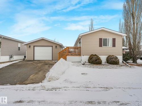Single-story home featuring tan horizontal siding and a detached single-car garage with a white overhead door - 151 3400 48 Street, Stony Plain, AB - Outdoor