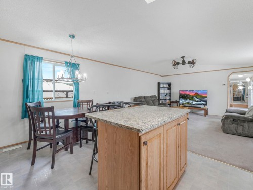 Well-appointed kitchen island with a light-toned granite countertop and wood-finish cabinetry - 151 3400 48 Street, Stony Plain, AB - Indoor