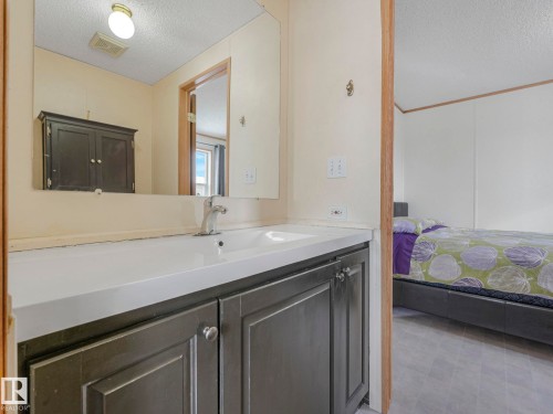 Bathroom vanity with an integrated sink and base cabinetry, featuring a large wall-mounted mirror - 151 3400 48 Street, Stony Plain, AB - Indoor Photo Showing Bathroom