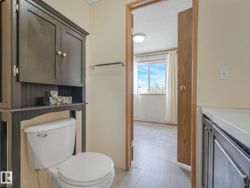 Bathroom featuring a dark wood-finish over-toilet cabinet, white toilet, and light gray flooring - 151 3400 48 Street, Stony Plain, AB - Indoor