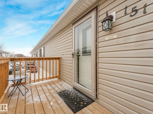 Exterior featuring a wooden deck with railing, light-colored vinyl siding, and a storm door - 151 3400 48 Street, Stony Plain, AB - Outdoor With Exterior