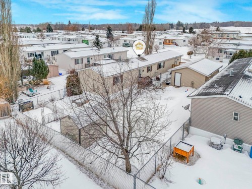 Fenced backyard with mature trees, a detached shed, and additional storage structures - 151 3400 48 Street, Stony Plain, AB - Outdoor