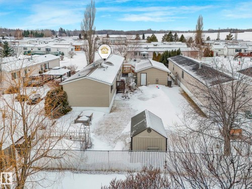 Rear exterior featuring a detached storage shed, a separate garage structure, and a fenced perimeter - 151 3400 48 Street, Stony Plain, AB - Outdoor