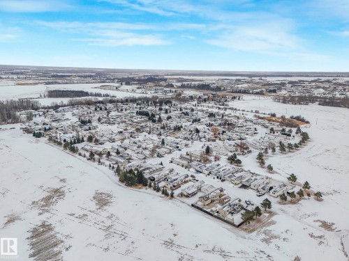 Aerial perspective showcasing a residential community surrounded by expansive snowy fields - 151 3400 48 Street, Stony Plain, AB - Outdoor With View