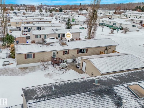 Single-story residence featuring light-colored siding, dark window shutters, and a rear deck - 151 3400 48 Street, Stony Plain, AB - Outdoor