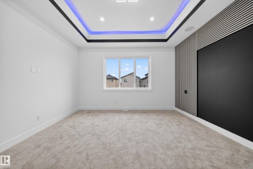 Recessed tray ceiling with integrated lighting, a built-in media wall with slatted detailing, and a multi-pane window - 4005 39 Street, Beaumont, AB - Indoor Photo Showing Other Room