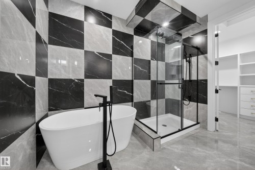 Bathroom featuring a freestanding soaking tub with floor-mounted matte black faucet, a glass-enclosed shower with matte black fixtures, and checkerboard-patterned wall tiling - 4005 39 Street, Beaumont, AB - Indoor Photo Showing Bathroom
