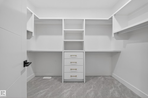 Custom closet system featuring white shelving and integrated drawers with gold-finish hardware - 4005 39 Street, Beaumont, AB - Indoor With Storage