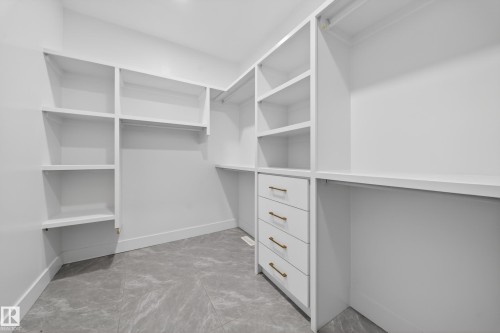 Custom closet system featuring white shelving, hanging rods, and built-in drawers with gold-toned hardware - 4005 39 Street, Beaumont, AB - Indoor With Storage