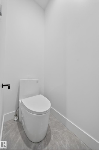 Modern white toilet fixture with a sleek design - 4005 39 Street, Beaumont, AB - Indoor Photo Showing Bathroom
