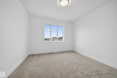 Bright interior space featuring a multi-pane window with white trim, neutral carpet flooring, and white painted walls - 4005 39 Street, Beaumont, AB - Indoor Photo Showing Other Room