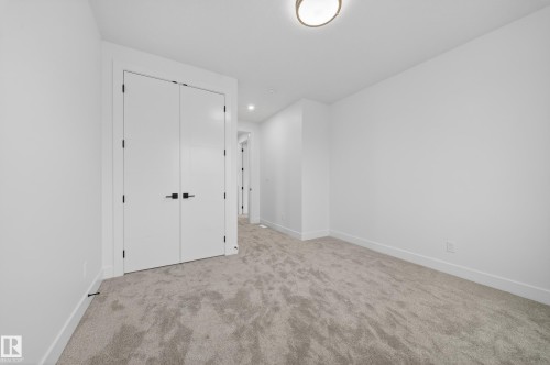 Spacious room featuring light gray carpet flooring, crisp white walls, white trim, and a contemporary ceiling light fixture - 4005 39 Street, Beaumont, AB - Indoor Photo Showing Other Room