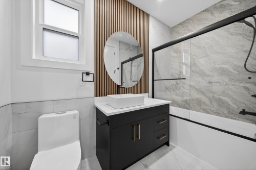 Bathroom featuring a black vanity with gold-tone hardware, a rectangular vessel sink, and a circular mirror - 4005 39 Street, Beaumont, AB - Indoor Photo Showing Bathroom