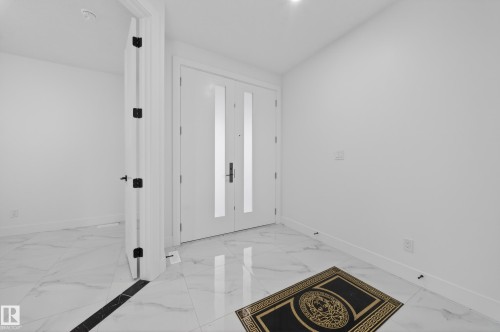 Bright entryway featuring dual white doors with frosted glass inserts - 4005 39 Street, Beaumont, AB - Indoor Photo Showing Other Room