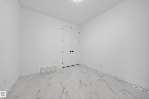 Room featuring large-format porcelain tile flooring with a marble-effect pattern, crisp white walls, and a pair of double doors with matte black hardware - 4005 39 Street, Beaumont, AB - Indoor