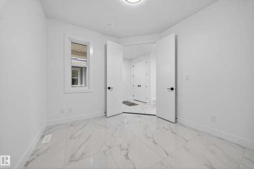 Bright room featuring white walls, large format marble-look tile flooring, and a single window with white trim - 4005 39 Street, Beaumont, AB - Indoor Photo Showing Other Room