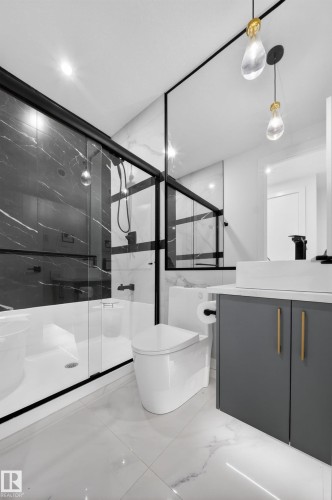 Bathroom featuring a black-framed glass shower enclosure, dark marbled wall tiling, a white freestanding tub, a contemporary toilet, and a grey vanity with gold-tone hardware - 4005 39 Street, Beaumont, AB - Indoor Photo Showing Bathroom