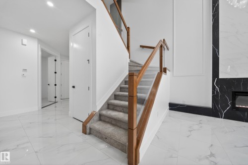 Staircase featuring wood-finish railings, glass panels, and carpeted treads with recessed lighting - 4005 39 Street, Beaumont, AB - Indoor Photo Showing Other Room