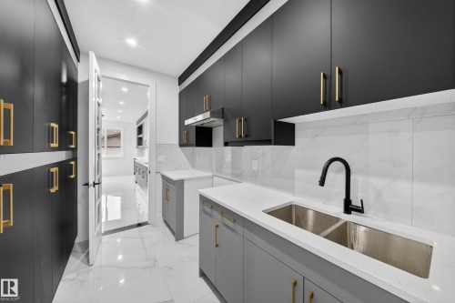 Modern kitchen featuring dark grey upper cabinetry and light grey lower cabinetry with gold-toned hardware - 4005 39 Street, Beaumont, AB - Indoor Photo Showing Kitchen With Double Sink With Upgraded Kitchen