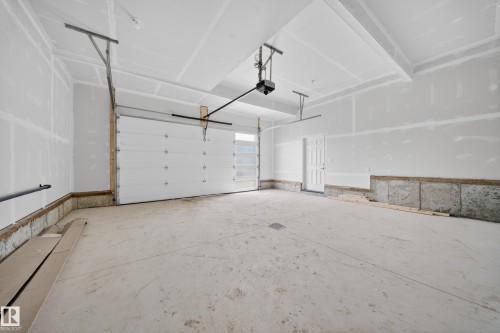 Spacious garage with a sectional overhead door and an automatic opener - 4005 39 Street, Beaumont, AB - Indoor Photo Showing Garage