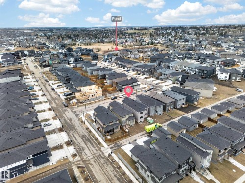 Neighborhood aerial showcasing residential streets, a mix of completed and under-construction homes, and a distant pond feature - 4005 39 Street, Beaumont, AB - Outdoor With View