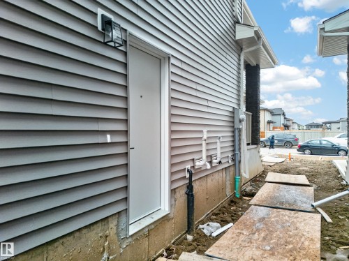 Gray horizontal siding exterior with a white entry door and a black exterior light fixture - 4005 39 Street, Beaumont, AB - Outdoor
