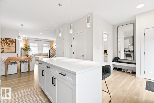Open-concept kitchen featuring a large island with a light-toned countertop, white shaker cabinetry, and black hardware - 6023 180 Avenue, Edmonton, AB - Indoor Photo Showing Kitchen With Upgraded Kitchen
