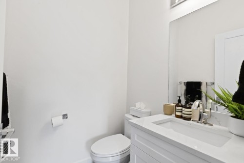 Bathroom featuring a white vanity with integrated sink, chrome faucet, and mirrored wall - 6023 180 Avenue, Edmonton, AB - Indoor Photo Showing Bathroom