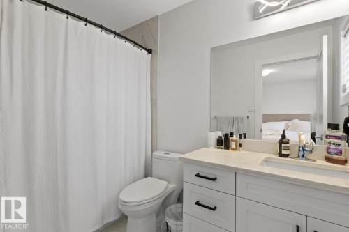 Contemporary bathroom featuring a white vanity with a light-toned countertop, an integrated sink, and black hardware - 6023 180 Avenue, Edmonton, AB - Indoor Photo Showing Bathroom
