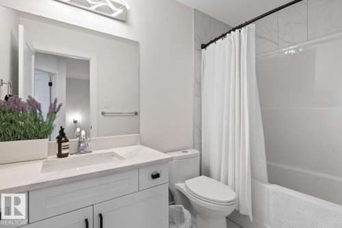 Bathroom featuring a white vanity with an undermount sink, a large mirror, and a contemporary light fixture - 6023 180 Avenue, Edmonton, AB - Indoor Photo Showing Bathroom