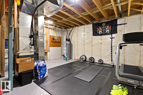 Unfinished basement space featuring exposed wood joists, ductwork, and a water heater - 6023 180 Avenue, Edmonton, AB - Indoor Photo Showing Basement