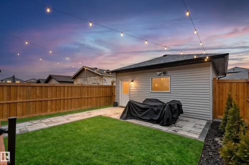 Fenced backyard featuring a manicured lawn, paver patio, and string lighting - 6023 180 Avenue, Edmonton, AB - Outdoor