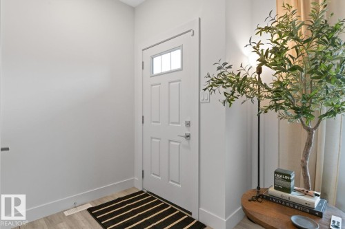 Entryway featuring a white paneled door with window inserts, light wood-finish flooring, and crisp white baseboards - 6023 180 Avenue, Edmonton, AB - Indoor Photo Showing Other Room