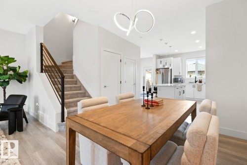 Bright dining area featuring wood-finish flooring, a contemporary chandelier, and an open concept layout - 6023 180 Avenue, Edmonton, AB - Indoor Photo Showing Dining Room