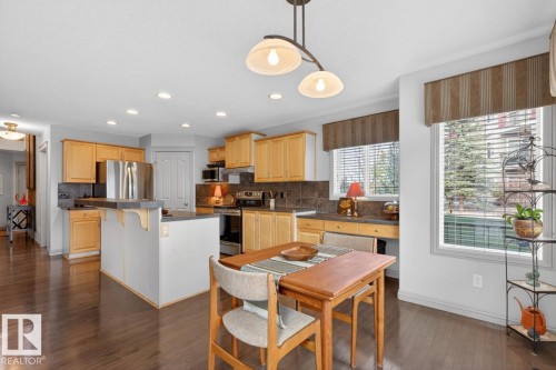 Kitchen featuring wood-finish flooring, light-toned cabinetry, dark countertops, and a central island with a breakfast bar - 2178 Haddow Drive, Edmonton, AB - Indoor