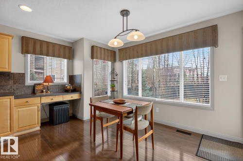 Kitchen dining area featuring wood-finish flooring and multiple windows with blinds - 2178 Haddow Drive, Edmonton, AB - Indoor