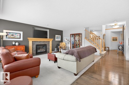 Living area featuring a fireplace with a stone surround and wood mantel, recessed alcove, and light carpet - 2178 Haddow Drive, Edmonton, AB - Indoor Photo Showing Living Room With Fireplace