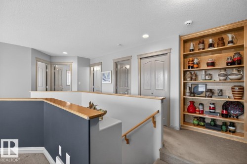Upper-level landing featuring a built-in wooden bookshelf, recessed lighting, carpet flooring, and a railing with a wood-finish top - 2178 Haddow Drive, Edmonton, AB - Indoor Photo Showing Other Room