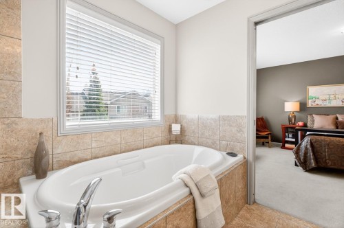 Built-in soaking tub with chrome fixtures, surrounded by light-toned tile - 2178 Haddow Drive, Edmonton, AB - Indoor Photo Showing Bathroom