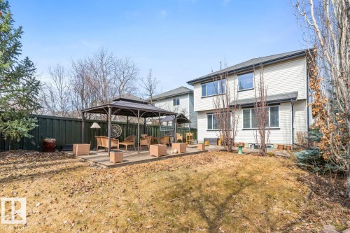 Spacious backyard featuring a built-in wooden deck with a metal gazebo structure, private green fencing, and mature trees - 2178 Haddow Drive, Edmonton, AB - Outdoor