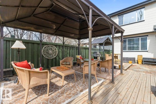 Outdoor living space featuring a metal-framed gazebo, a wooden privacy fence, and a multi-level deck constructed with wood planks and flagstone - 2178 Haddow Drive, Edmonton, AB - Outdoor With Deck Patio Veranda