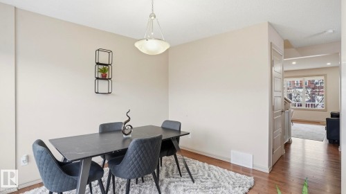 Dining area featuring a contemporary chandelier, light-toned wall paint, and wood-finish flooring - 8210 180 Avenue Nw, Edmonton, AB - Indoor Photo Showing Dining Room