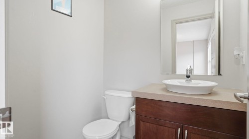 Modern vanity featuring a vessel sink with a chrome faucet, a stone-finish countertop, and dark wood cabinetry - 8210 180 Avenue Nw, Edmonton, AB - Indoor Photo Showing Bathroom