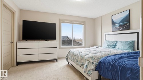 Bedroom featuring light-toned walls, a large window, light-colored carpeting, a door with a polished knob, and a ceiling-mounted light fixture - 8210 180 Avenue Nw, Edmonton, AB - Indoor Photo Showing Bedroom