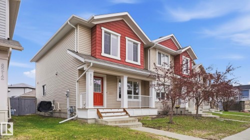 Two-story exterior featuring beige horizontal siding with red shingle accents and white trim - 8210 180 Avenue Nw, Edmonton, AB - Outdoor With Facade