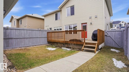 Rear yard featuring a wood deck with stairs, a red exterior door, and a concrete pathway - 8210 180 Avenue Nw, Edmonton, AB - Outdoor With Deck Patio Veranda With Exterior