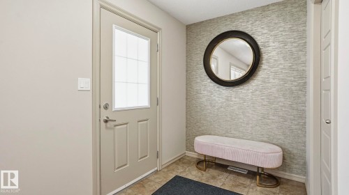 Entryway featuring a panel door with frosted glass insert, textured accent wall, and ceramic tile flooring - 8210 180 Avenue Nw, Edmonton, AB - Indoor Photo Showing Other Room